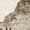 Steinbruch Kolbenstein bei Montlingen mit Dienstbahngeleisen, Kran und Arbeitern im Vordergrund sowie der gesprengten Felswand und Arbeitern in der Wand im Hintergrund. 1913