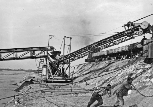 Kiesgewinnung mit Schwimmbagger und Fließband zur Dienstbahn, Arbeiter ziehen an einer Kette. Kiesbaggerungen, Auswirkungen auf Rheinsohle, 1920–1950